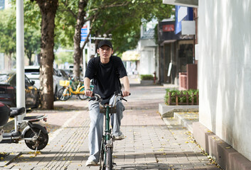 handsome young Asian man with hat riding bike on street