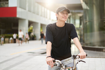 handsome young Asian man with hat riding bike on street