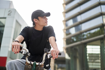 handsome young Asian man with hat riding bike on street