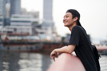 happy young Asian man relaxing at waterfront