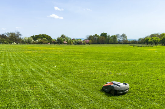 freshly mowed green lawn with visible stripes as before and after concept on lush green meadow background. robot gardening assistant