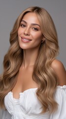 Fototapeta premium Attractive smiling young woman with blonde wavy hair in a white top poses against a neutral background in a studio setting
