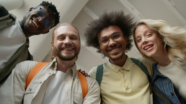 Bottom view group of diverse college friends four multiracial students smiling hello greeting positive happy in university hall Caucasian woman girl African American men guys multicultural friendship