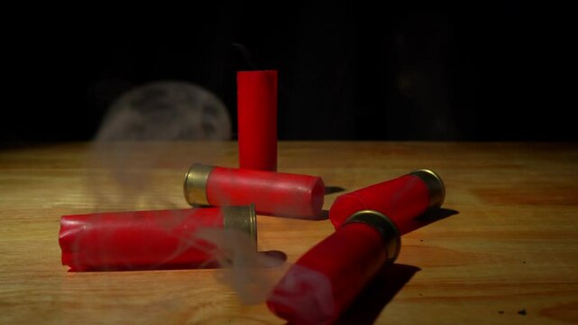 Shotgun shells fall steaming after firing and reloading onto a rough wooden floor