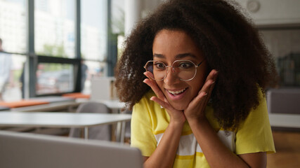 African American happy excited girl student using laptop studying online pass exam good result news...