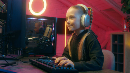 Caucasian teenager little child concentrated worried web net streaming daughter girl kid playing computer monitor match video game online gaming addiction play stream at home neon light gamer weekend