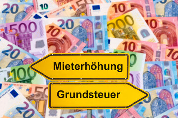 Ein Wegweiser mit dem Aufdruck Mieterhöhung und Grundsteuer steht vor vielen Euro Geldschainen -...