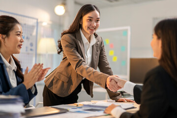 A woman shakes hands with another woman in a business setting