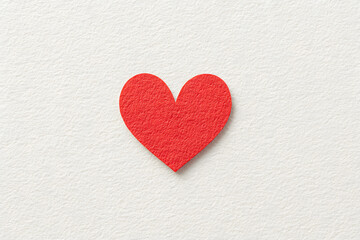 Obraz premium Red Heart: A single, vibrant red heart, cut from paper, is the focus of this minimalist image. The heart, a timeless symbol of love and passion, is isolated on a textured background. 