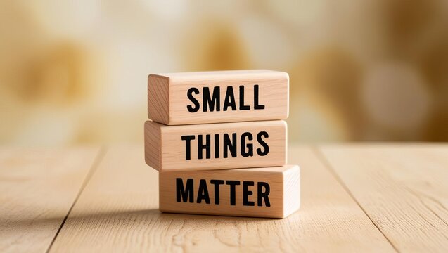 Three wooden blocks stacked on a table display the phrase "SMALL THINGS MATTER" against a soft, warm background.
