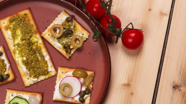 Piatto con tartine di formaggio e verdure, pomodorini a grappolo sul tavolo