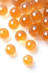 Golden, translucent spheres scattered on a bright white surface. Close-up shot