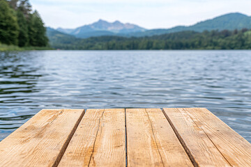 A wooden pier stretches over tranquil lake waters offe stunning mountain views in the distance.