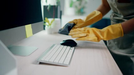 Detailed view of a professional cleaner wearing gloves while thoroughly disinfecting an office computer keyboard