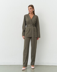 Elegant female model showcasing a chic olive green outfit in a minimalist studio setting