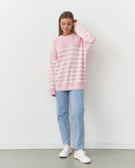 Fashionable woman poses in soft pink stripes against a clean studio backdrop
