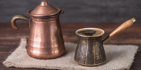 Traditional coffee brewing setup featuring a copper pot and cup with roasted coffee beans on a rustic cloth