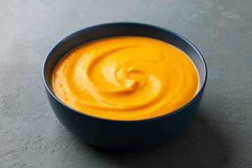 Pumpkin, butternut squash soup in bowl. Grey background. Close up.