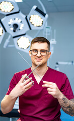 Surgeon readying for surgery. A surgeon in scrubs holds surgical instruments in a modern operating...