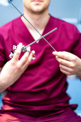 Surgeon prepping instruments. Surgeon in maroon scrubs holds surgical instruments, focused on...