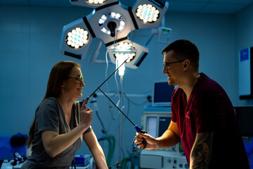 Surgical team sharing a laugh. Two medical professionals exchange playful gestures while preparing...