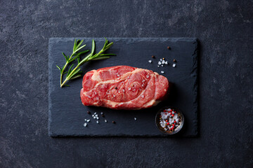Fresh Raw Steak with Herbs on Slate Board. Dark background. Top view.