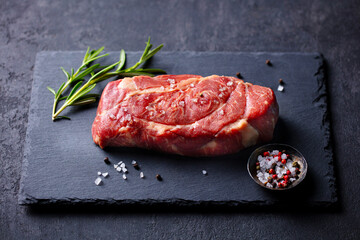 Fresh raw steak with herbs on slate board. Dark background. Close up.
