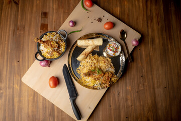 Spicy chicken biryani in pot. served with onion raita	