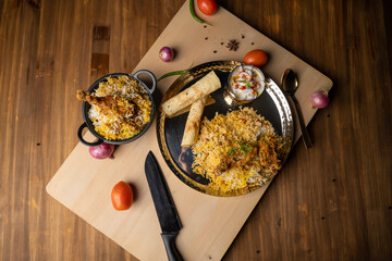 Spicy chicken biryani in pot. served with onion raita	