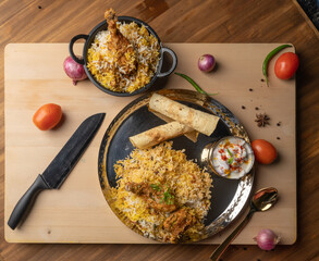 Spicy chicken biryani in pot. served with onion raita	