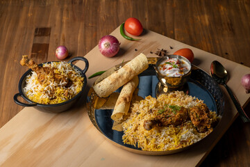 Spicy chicken biryani in pot. served with onion raita	