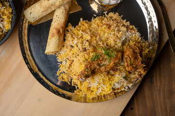 Spicy chicken biryani in pot. served with onion raita	