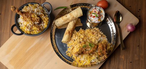 Spicy chicken biryani in pot. served with onion raita	
