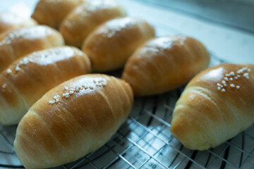 Freshly baked golden bread rolls with sugar crystals on top, cooling on a wire rack.