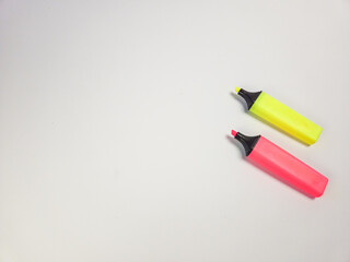 Two colorful highlighters on a plain white background for creative projects