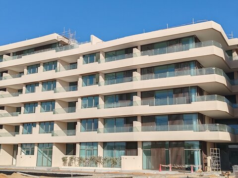 Under construction residential building with Cream color.
Exterior view of 05 story building with modern design and having black glas windows. Highrise building with balcony Blue SKY background.