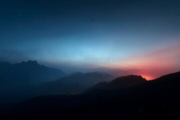 Fototapeta premium Silhouette of mountain range at sunset, blue and pink hues in sky, creating serene, tranquil atmosphere, ideal for travel or nature background