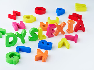 Obraz premium Dyslexia word bright colorful wooden toy blocks in white background. Dyslexia concept. difficulty with fast reading, writing words, education learning elementary school kids.
