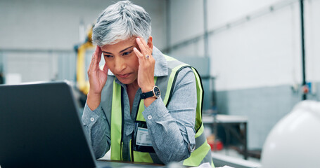 Mature, woman and laptop with headache in workshop for engineering fatigue, burnout and website...
