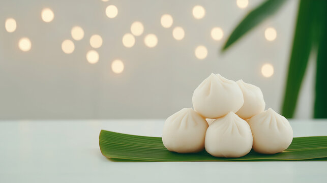 Delicious steamed baos arranged on a fresh green leaf with soft background bokeh lights.