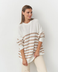 Chic fashion with a model in a cozy striped sweater and neutral pants