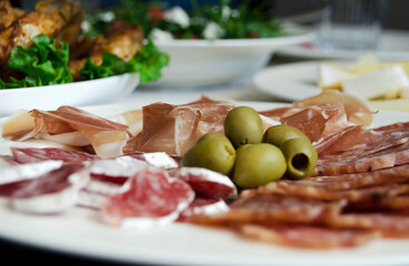 Serving tray with a circular arrangement of meats salami, pepperoni, prosciutto and green olives on...