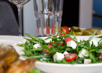 Salad with green fresh arugula, cherry tomatoes and white cheese.