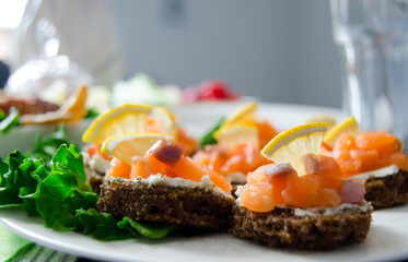 Delicious appetizer canapes of black bread, lemon, cream cheese and red fish salmon.Buffet snacks.