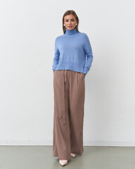 Elegant female model showcasing contemporary fashion in a minimalist studio setting