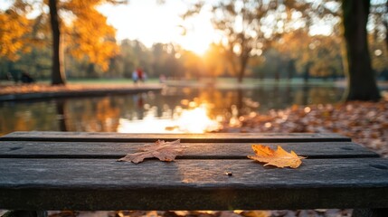 Close up of a rustic table adorned with vibrant autumn leaves beside a picturesque lake bathed in sunset light, offering a cozy and inviting atmospheric setting.