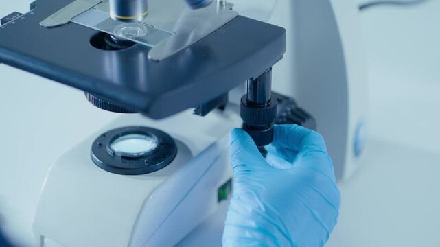 A CloseUp Image of a Scientist Working Diligently with a Microscope Inside a Laboratory