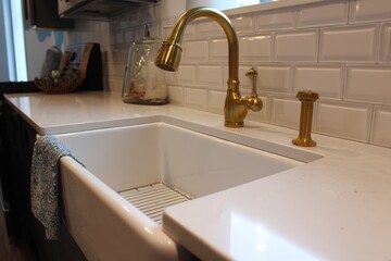 Elegant Farmhouse Sink with Gold Faucet in a Modern Kitchen Featuring White Granite and Stylish Backsplash