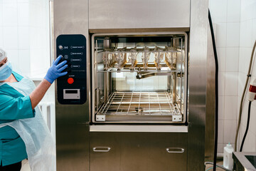 Medical worker starting sterilizer machine in lab