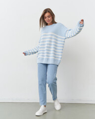 Stylish model showcases playful fashion in soft blue hues during studio shoot